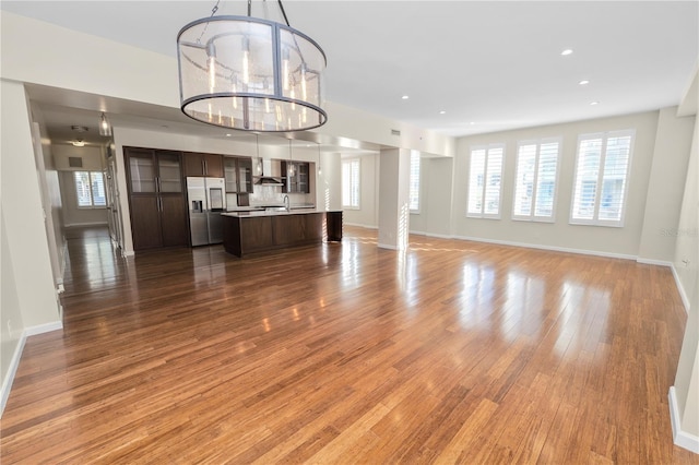 unfurnished living room featuring hardwood / wood-style flooring, sink, and a chandelier