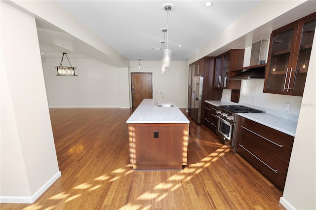 kitchen featuring sink, dark wood-type flooring, premium appliances, an island with sink, and decorative light fixtures