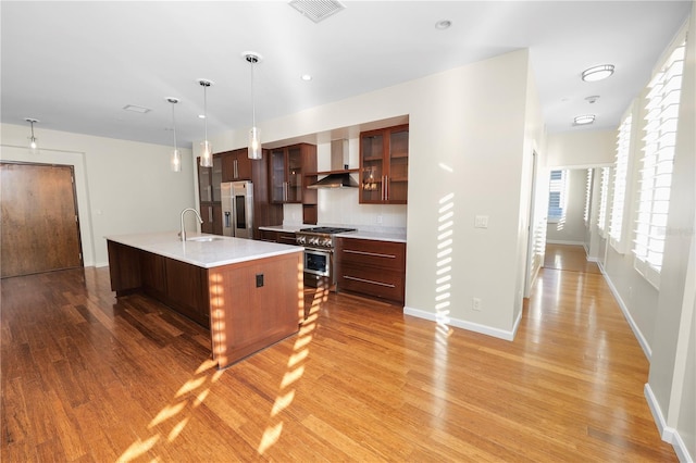 405 Central Ave Unit 210, Saint Petersburg, FL 33701 - kitchen with stainless steel appliances, a sink, light wood finished floors, light countertops, and wall chimney range hood