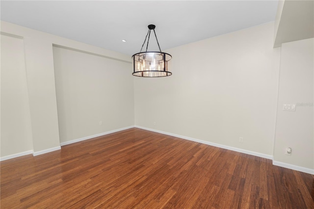 spare room with dark hardwood / wood-style floors and a notable chandelier