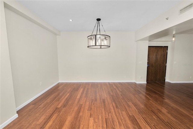 spare room featuring dark hardwood / wood-style floors and an inviting chandelier