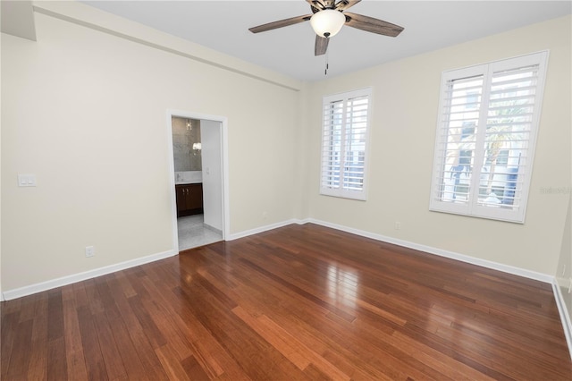 spare room featuring ceiling fan, a healthy amount of sunlight, and dark wood-type flooring