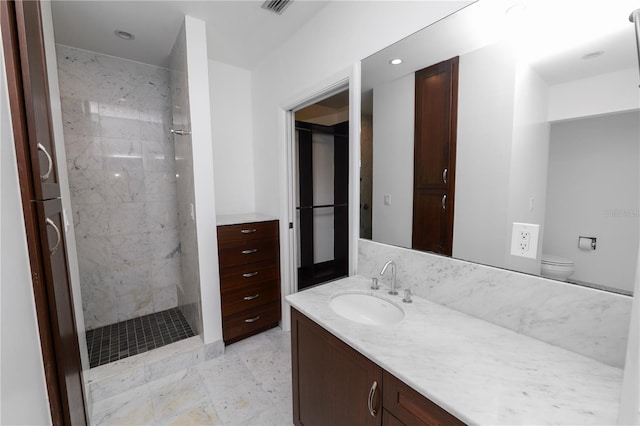 bathroom with tiled shower, vanity, and toilet