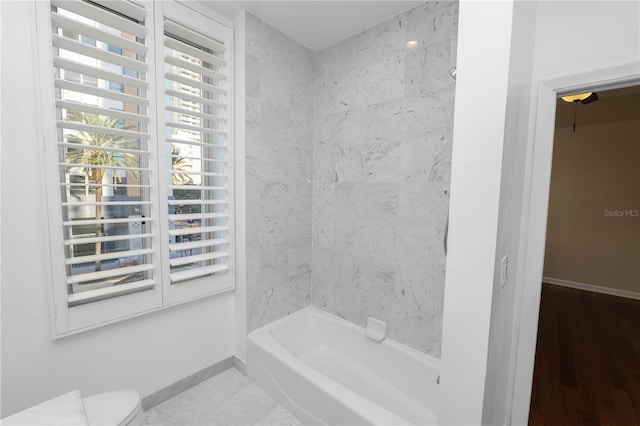 bathroom featuring hardwood / wood-style floors, toilet, and tiled shower / bath