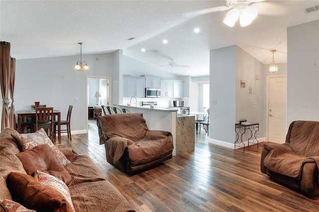 living room with a textured ceiling, dark hardwood / wood-style floors, lofted ceiling, and ceiling fan with notable chandelier