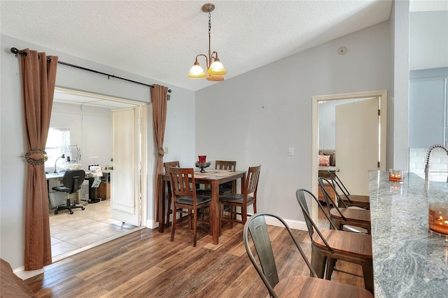 dining room with a chandelier, a textured ceiling, and light wood-type flooring