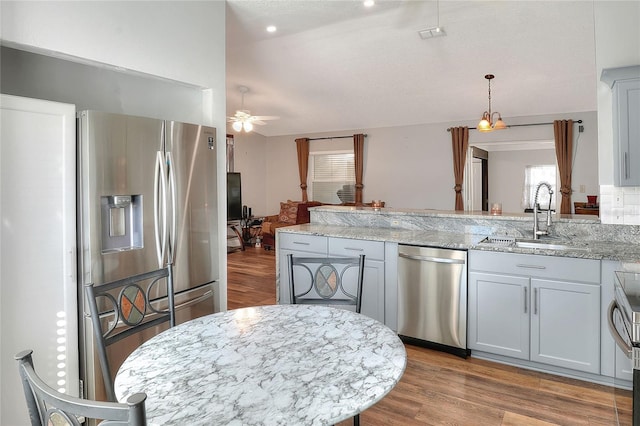 kitchen featuring ceiling fan, sink, stainless steel appliances, light stone counters, and light hardwood / wood-style floors