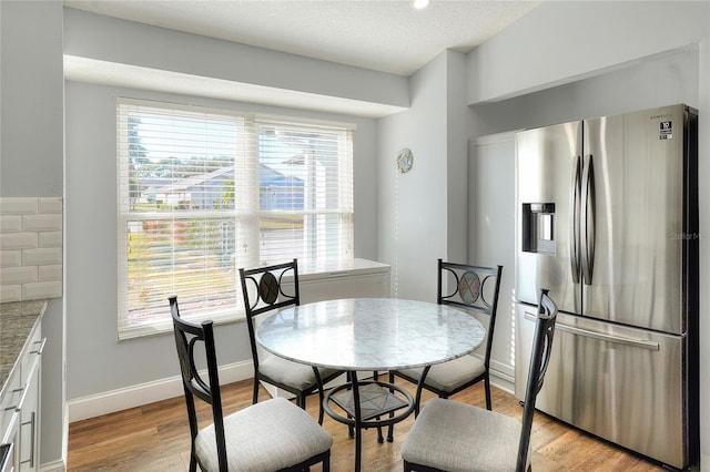 dining space featuring a textured ceiling and light hardwood / wood-style flooring