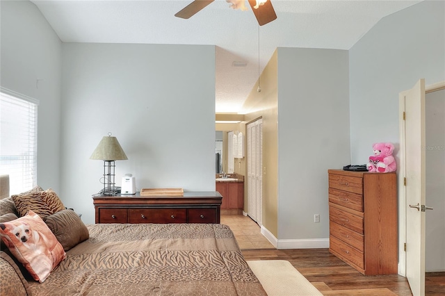 bedroom with ensuite bathroom, light hardwood / wood-style floors, ceiling fan, and vaulted ceiling