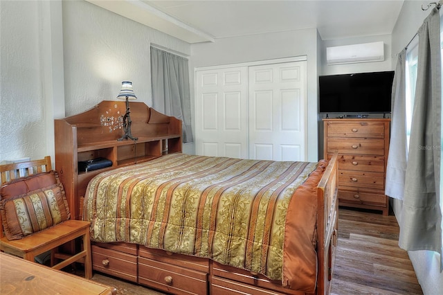 bedroom featuring an AC wall unit, a closet, and wood-type flooring