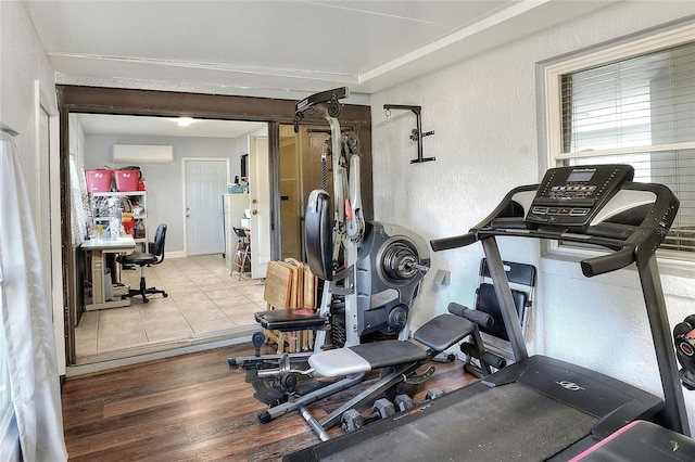 workout area featuring an AC wall unit and light hardwood / wood-style flooring