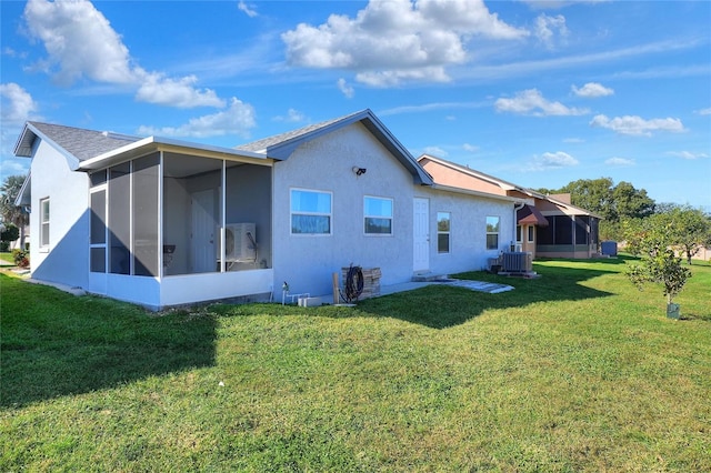 rear view of property with a lawn, a sunroom, and central AC unit