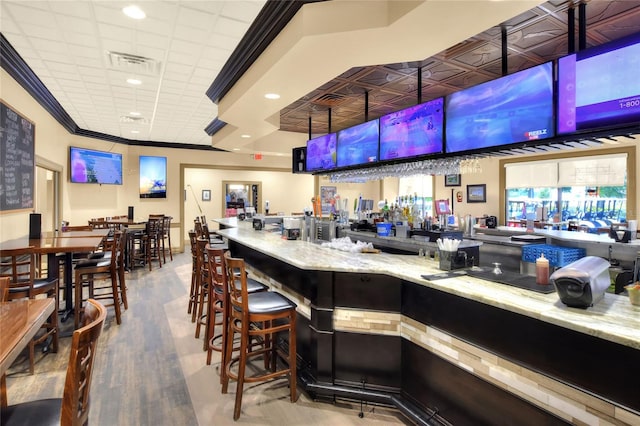 bar with light stone countertops, hardwood / wood-style floors, and ornamental molding