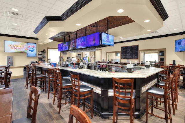 bar with light stone countertops and ornamental molding