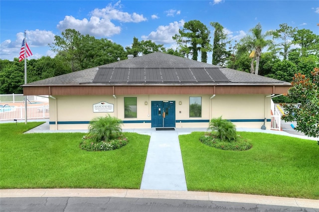 view of front of home with solar panels and a front lawn