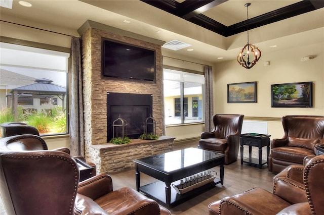 living room featuring beam ceiling, crown molding, hardwood / wood-style floors, a chandelier, and a fireplace