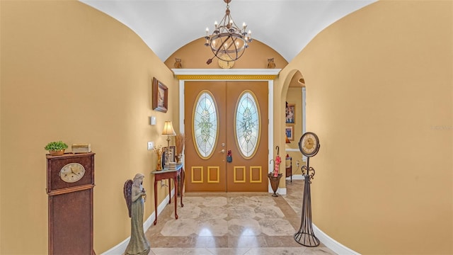 foyer with a chandelier, french doors, and vaulted ceiling