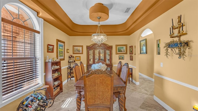 dining room with a raised ceiling and a chandelier