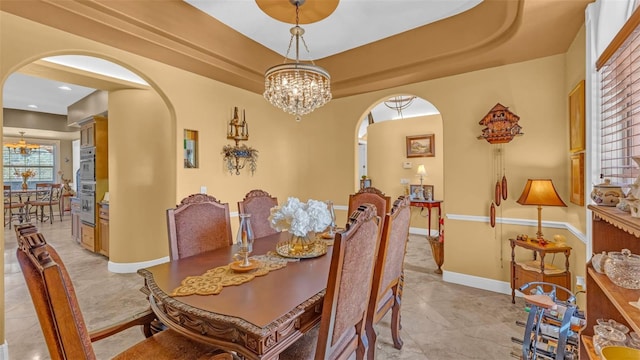 tiled dining space featuring a raised ceiling and an inviting chandelier