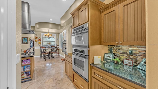 kitchen featuring dark stone countertops, decorative backsplash, pendant lighting, and a chandelier