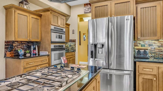 kitchen with decorative backsplash, dark stone countertops, and appliances with stainless steel finishes