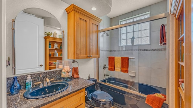 full bathroom featuring a textured ceiling, vanity, toilet, and bath / shower combo with glass door