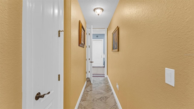 hallway with light tile patterned flooring and a textured ceiling