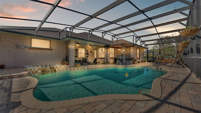 pool at dusk featuring a patio and glass enclosure