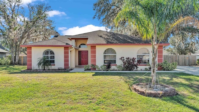 view of front of house with fence, a front lawn, and stucco siding