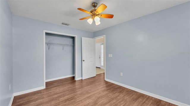 unfurnished bedroom with baseboards, a closet, visible vents, and wood finished floors