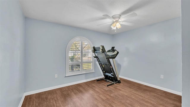 exercise area with ceiling fan, baseboards, and wood finished floors