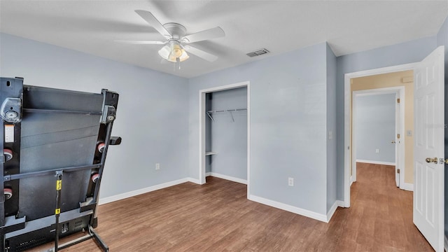 bedroom with a closet, visible vents, a ceiling fan, wood finished floors, and baseboards