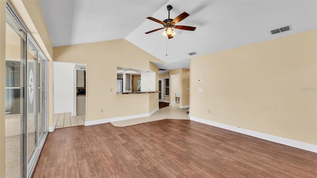 unfurnished room with ceiling fan, visible vents, vaulted ceiling, and wood finished floors