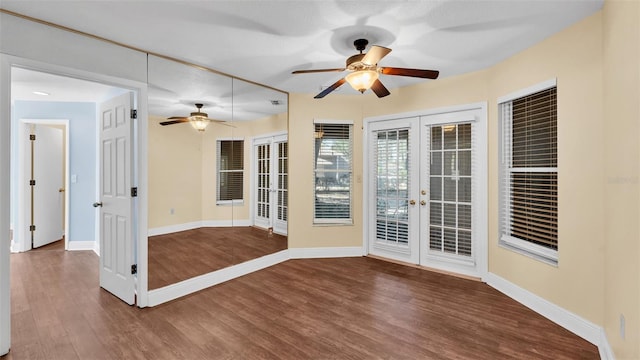 interior space featuring a ceiling fan, baseboards, wood finished floors, and french doors