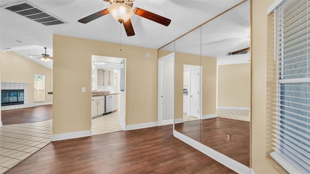 spare room featuring a tile fireplace, visible vents, ceiling fan, and wood finished floors