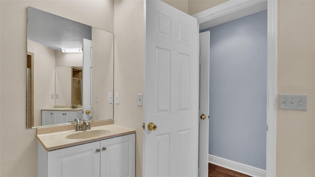 bathroom featuring a textured ceiling, vanity, and baseboards