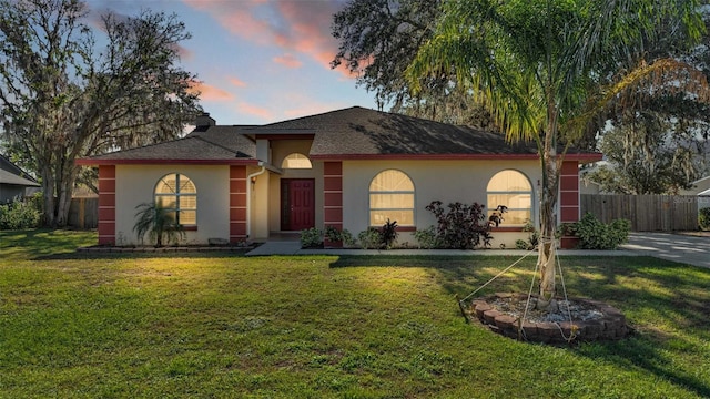 view of front facade with a yard, fence, and stucco siding