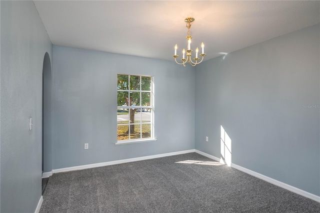 empty room featuring dark carpet and a chandelier