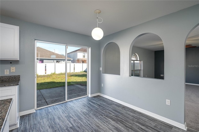 unfurnished dining area with dark wood-type flooring