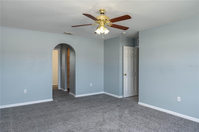 unfurnished room with ceiling fan, dark carpet, and a textured ceiling