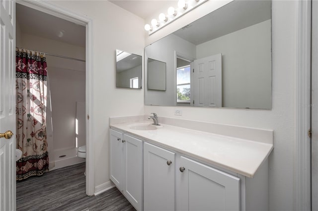 bathroom featuring hardwood / wood-style flooring, vanity, toilet, and walk in shower