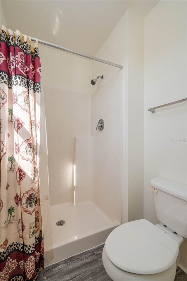 bathroom with a shower with shower curtain, hardwood / wood-style flooring, and toilet