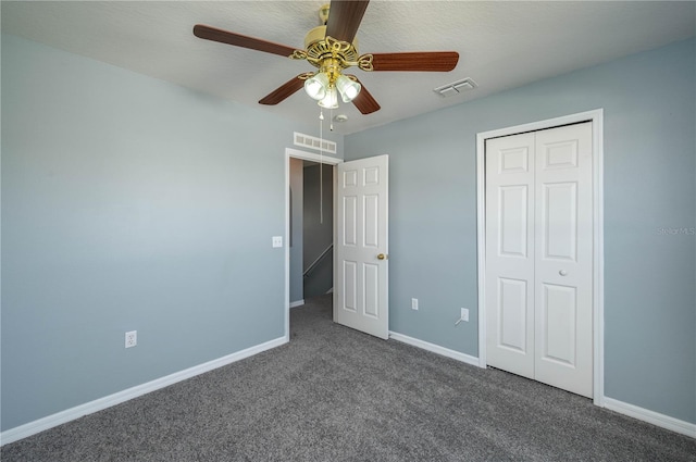 unfurnished bedroom featuring dark colored carpet, a textured ceiling, a closet, and ceiling fan