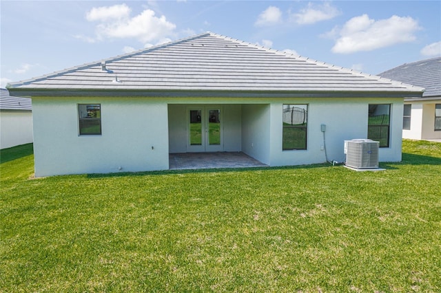 rear view of house with central AC unit, a yard, a patio, and french doors