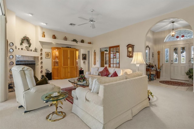 living room featuring ceiling fan, light colored carpet, and a tiled fireplace