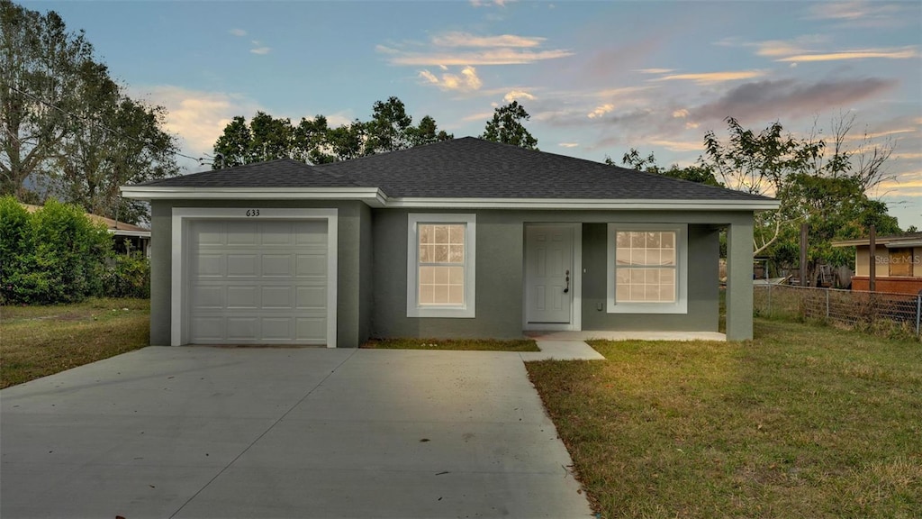 ranch-style home featuring a garage and a lawn