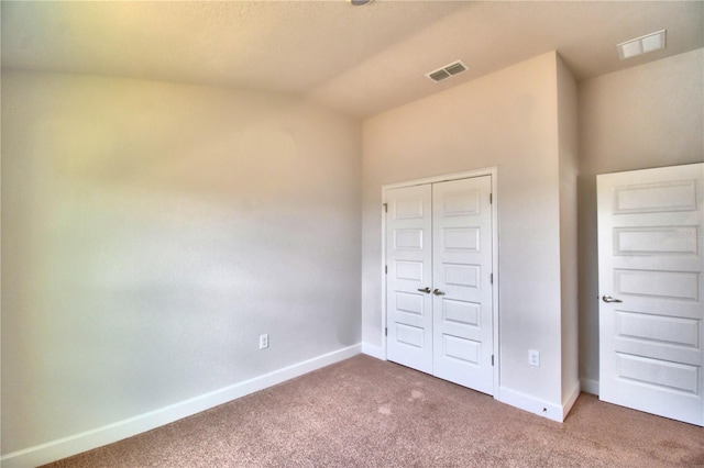 unfurnished bedroom featuring carpet floors, vaulted ceiling, and a closet