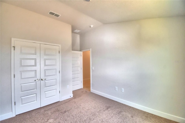 unfurnished bedroom featuring carpet, vaulted ceiling, and a closet