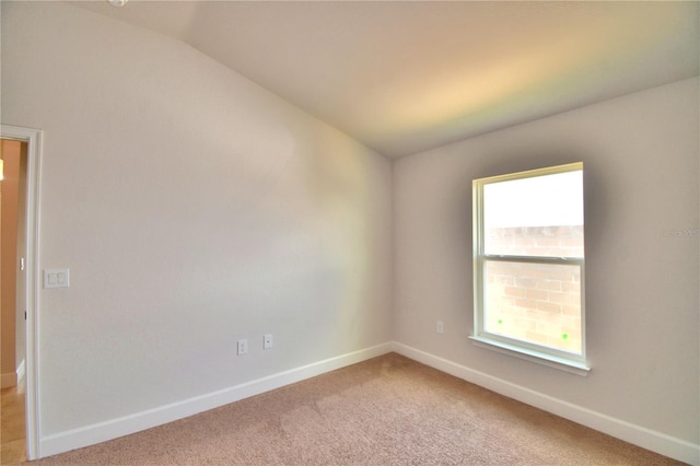 unfurnished room featuring light carpet and vaulted ceiling