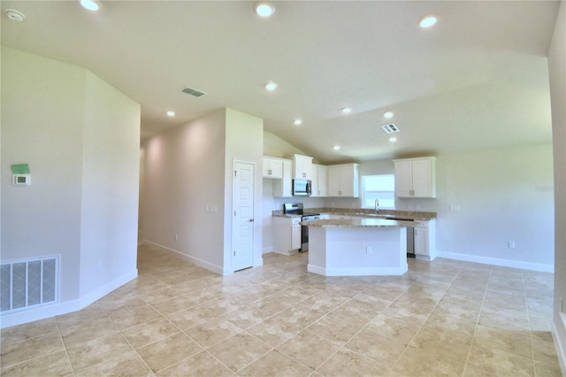 kitchen with a center island, white cabinets, sink, vaulted ceiling, and appliances with stainless steel finishes